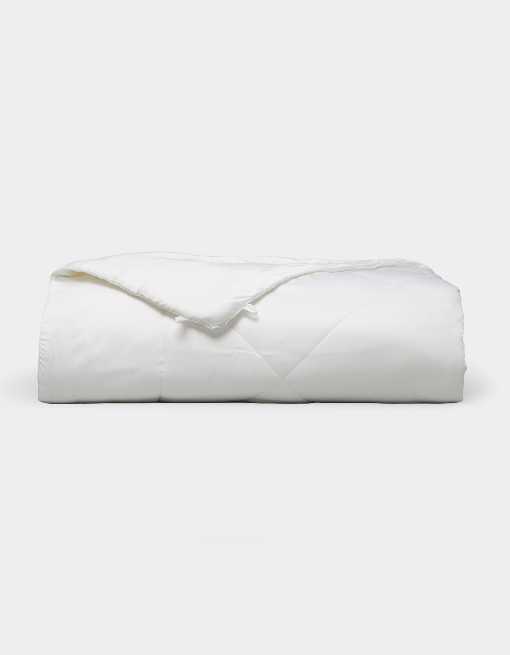 The Bamboo Viscose All Season Comforter by Cozy Earth, featuring a neatly folded white design with a subtle sheen, is displayed against a plain light background.|Filling:Standard 