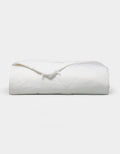 The Bamboo Viscose All Season Comforter by Cozy Earth, featuring a neatly folded white design with a subtle sheen, is displayed against a plain light background.|Filling:Standard 