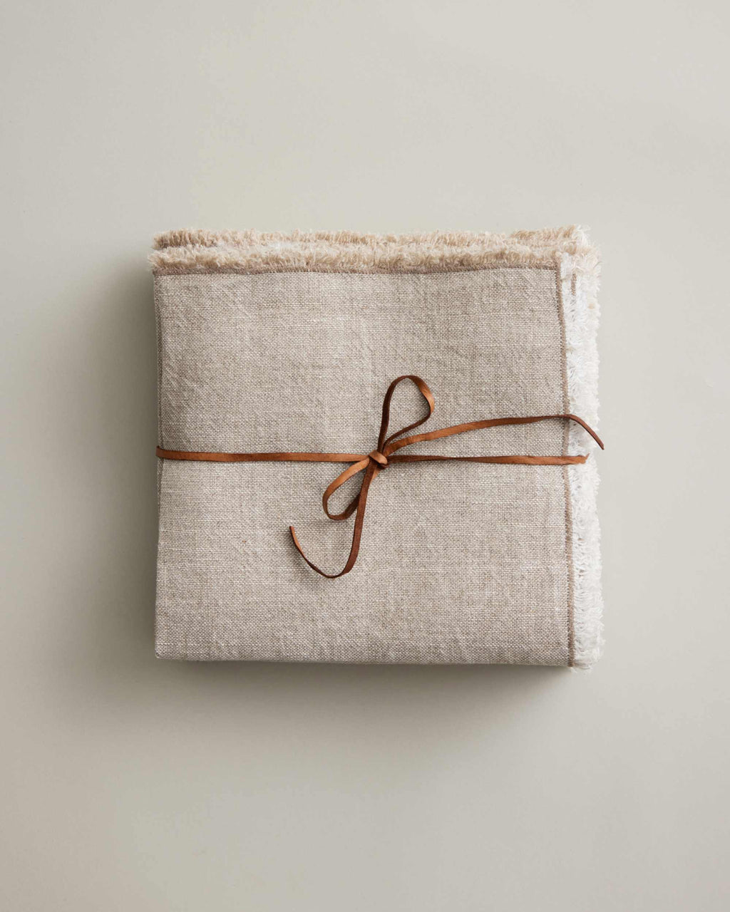 Natural-colored CULTIVER Fia napkins folded with leather tie, soft linen table linens for elegant dining.