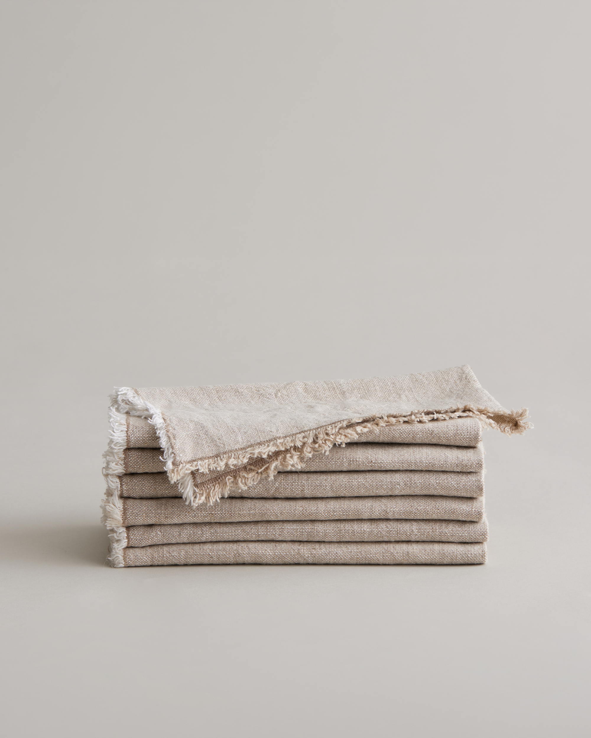 Stack of CULTIVER Fia Napkins in natural linen, soft and textured table linen for elegant dining settings.