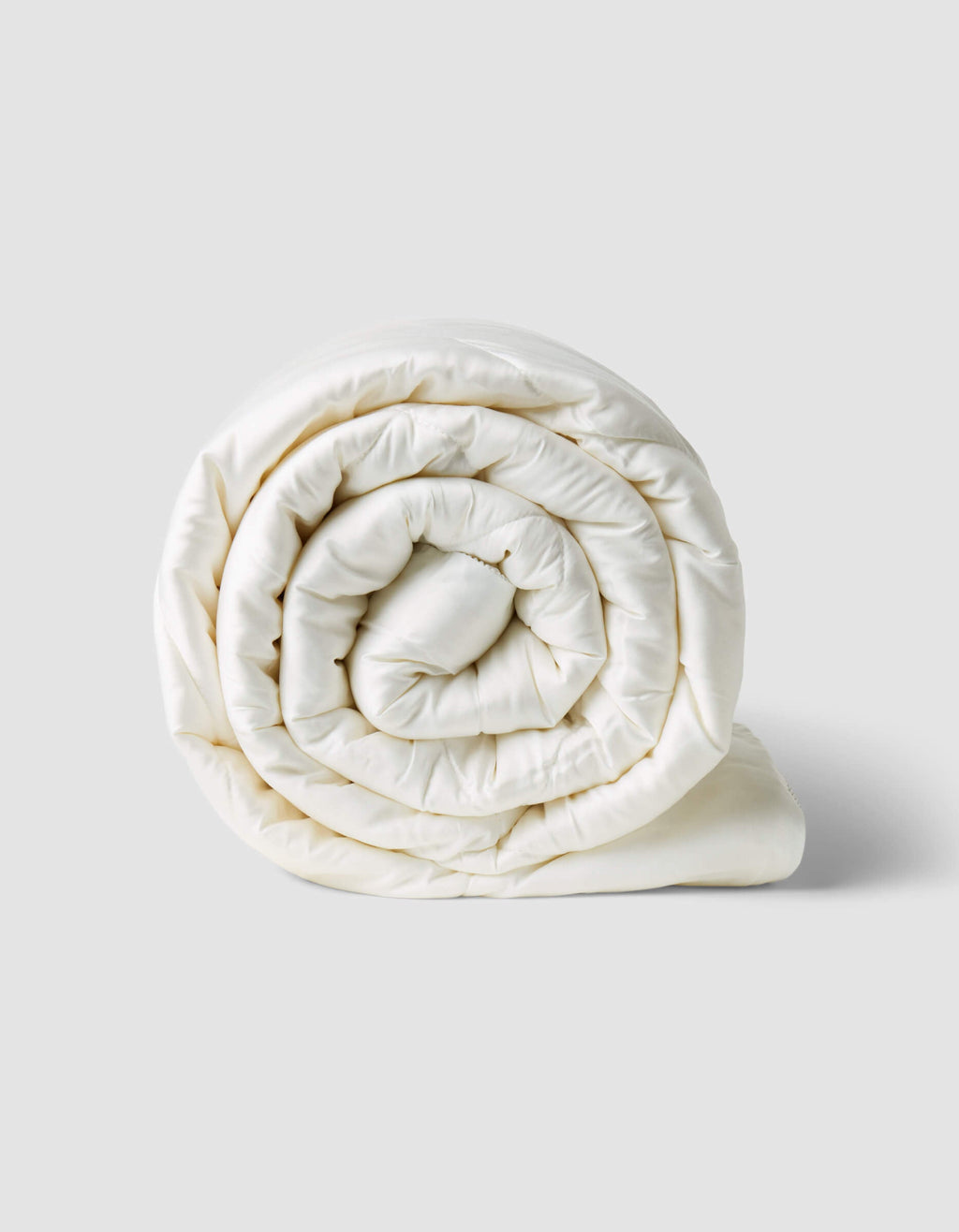 The Cozy Earth Bamboo Viscose Comforter, in crisp white, is shown neatly rolled on a plain light gray background.|Filling:Standard